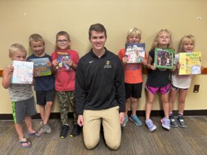 college athlete and young kids with books